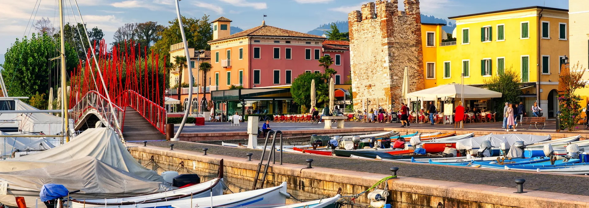 Boote im Altstadthafen von Bardolino am Gardasee mit bunten Gebäuden im Hintergrund.