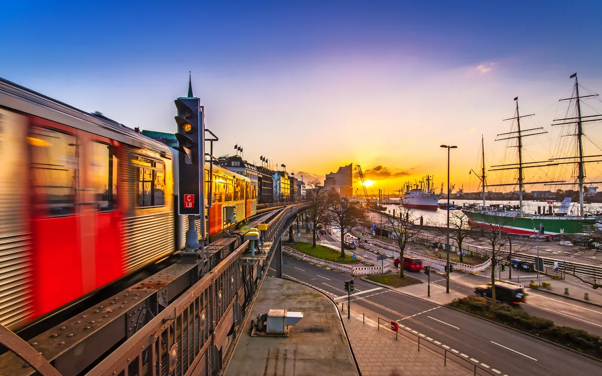 Eine U-Bahn fährt bei Sonnenuntergang über eine Brücke in einer Stadt.