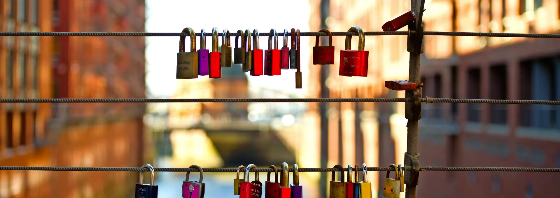 © VRD - stock.adobe.com Bunte Vorhängeschlösser an einem Brückengeländer über einem Kanal.