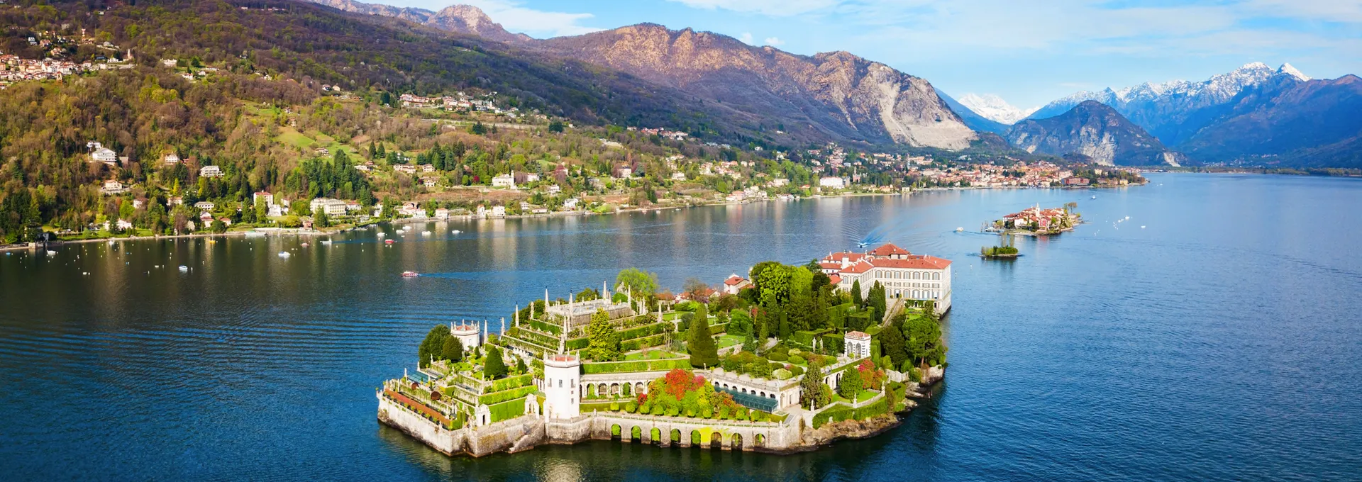 © saiko3p - stock.adobe.com Luftaufnahme einer Insel mit historischem Gebäude in einem See umgeben von Bergen.