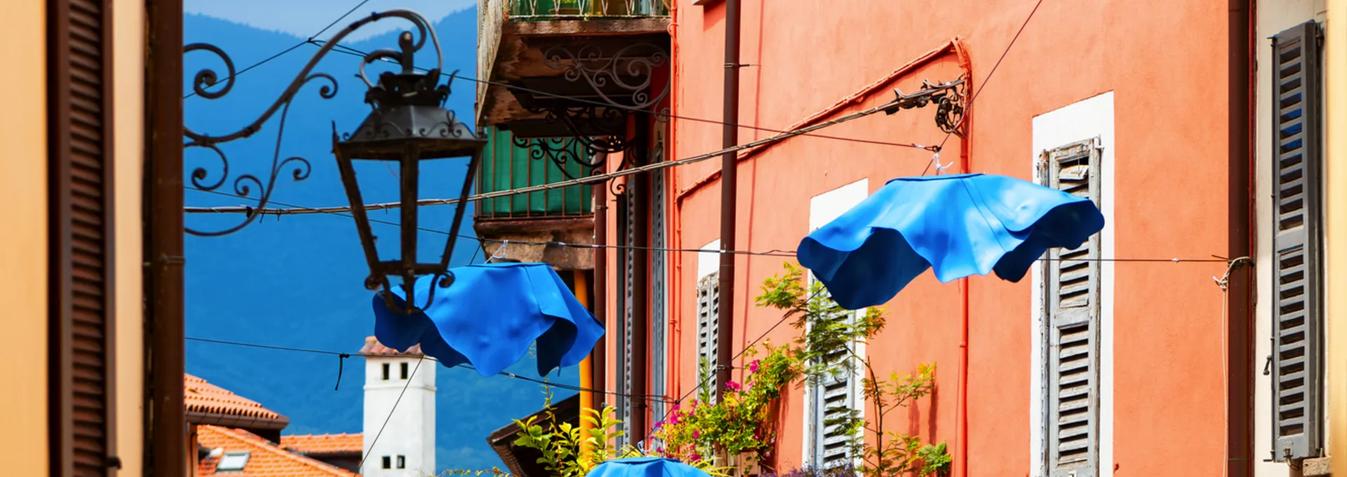 © ON-Photography - stock.adobe.com Gasse mit bunten Gebäuden und blauen Regenschirmen über der Straße
