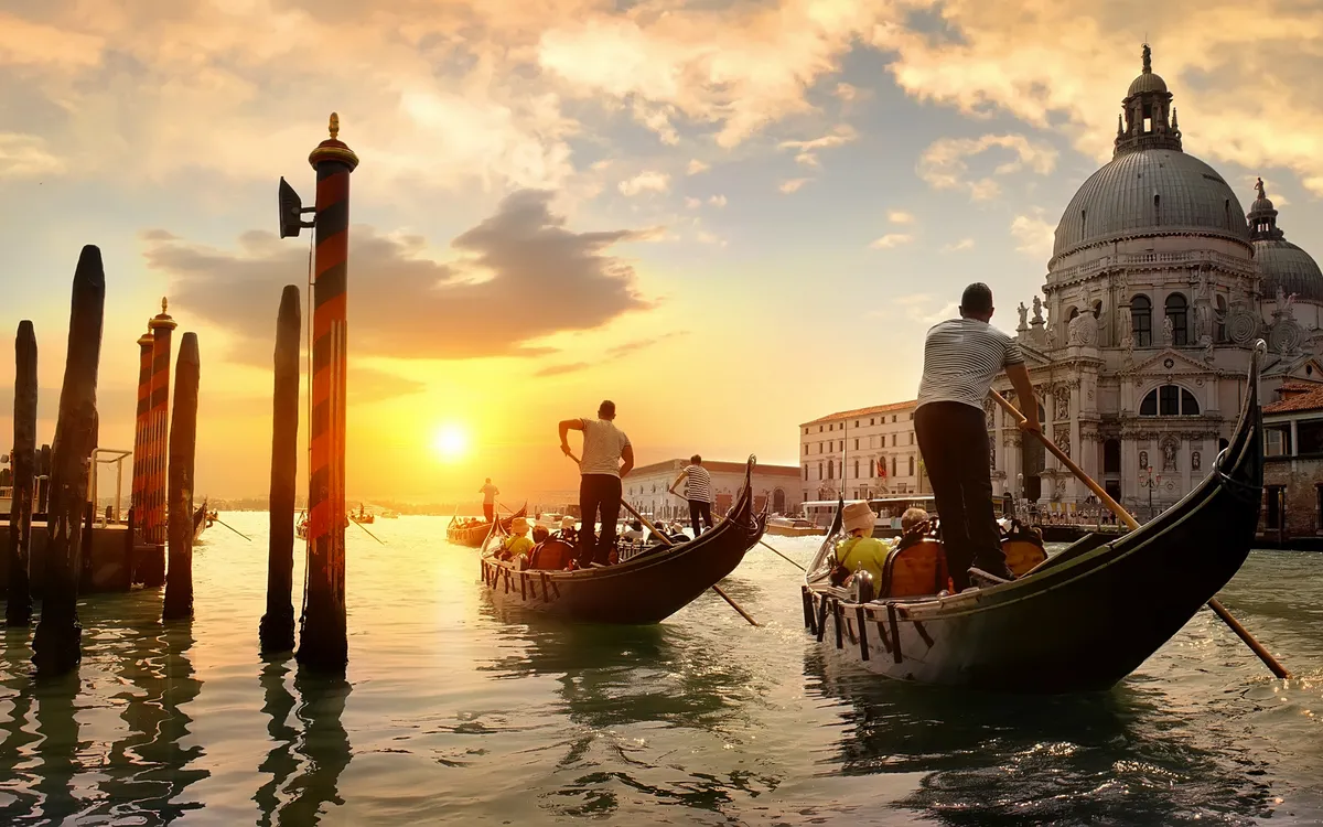 Gondeln fahren bei Sonnenuntergang vor Santa Maria della Salute in Venedig.
