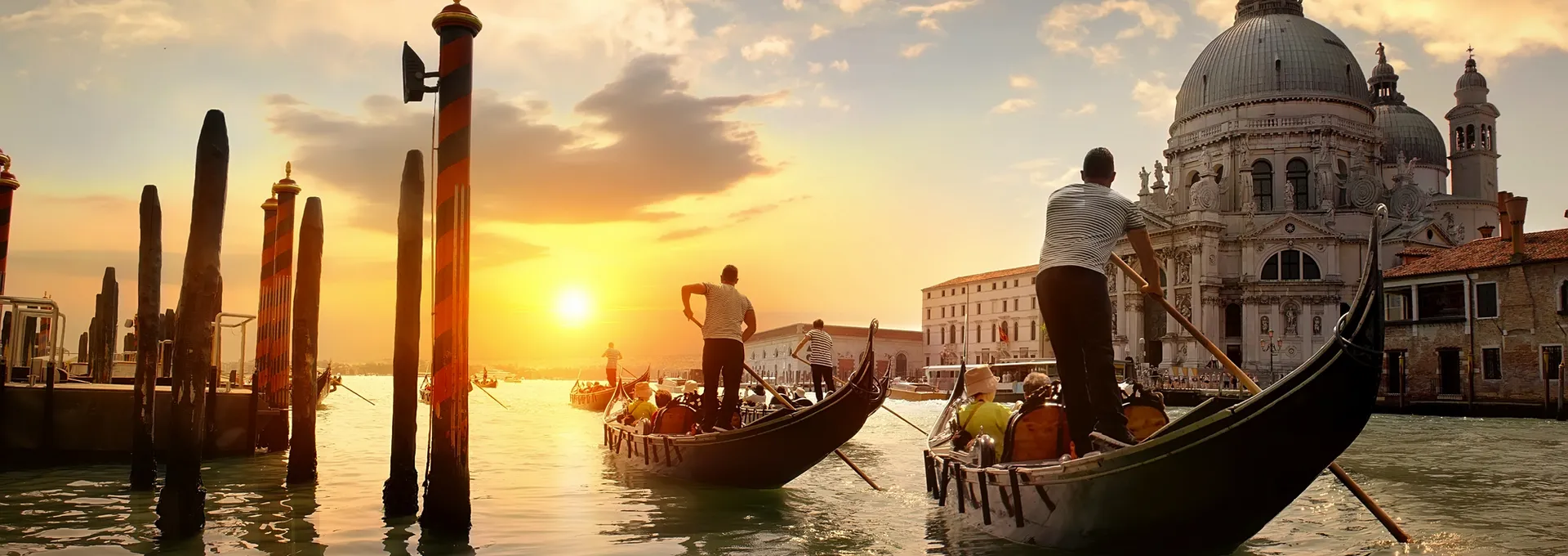 © Givaga - stock.adobe.com Gondeln fahren bei Sonnenuntergang vor Santa Maria della Salute in Venedig.