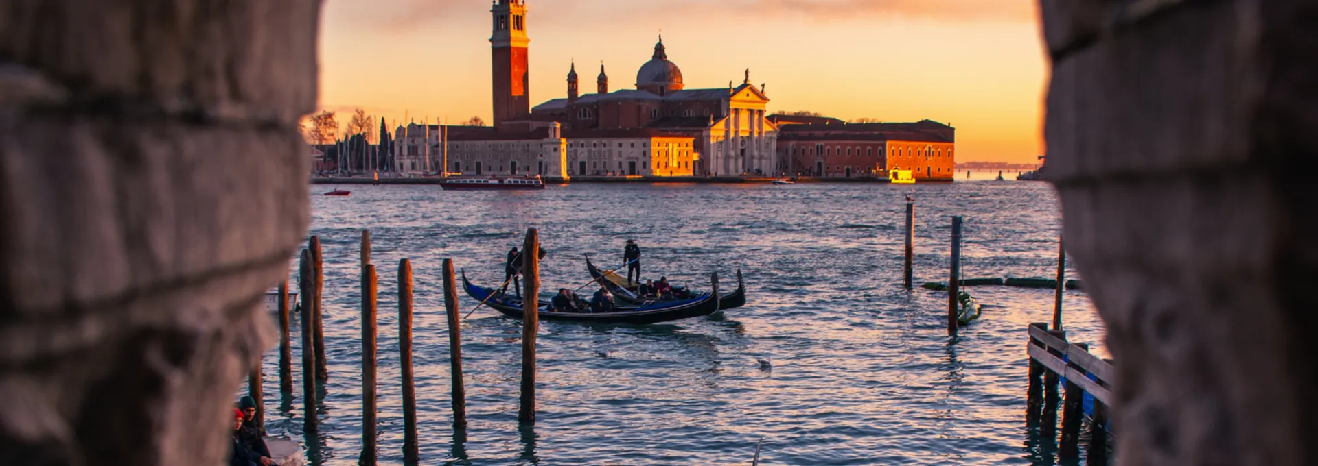 © Volodymyr Bakulin - stock.adobe.com Gondeln auf dem Wasser mit Blick auf venezianische Insel bei Sonnenuntergang.