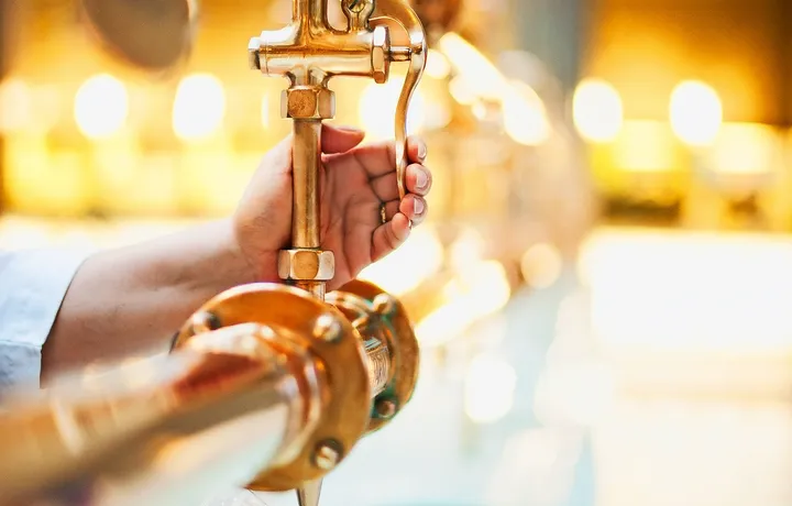 Eine Hand füllt ein Glas am Heilwasserausschank.