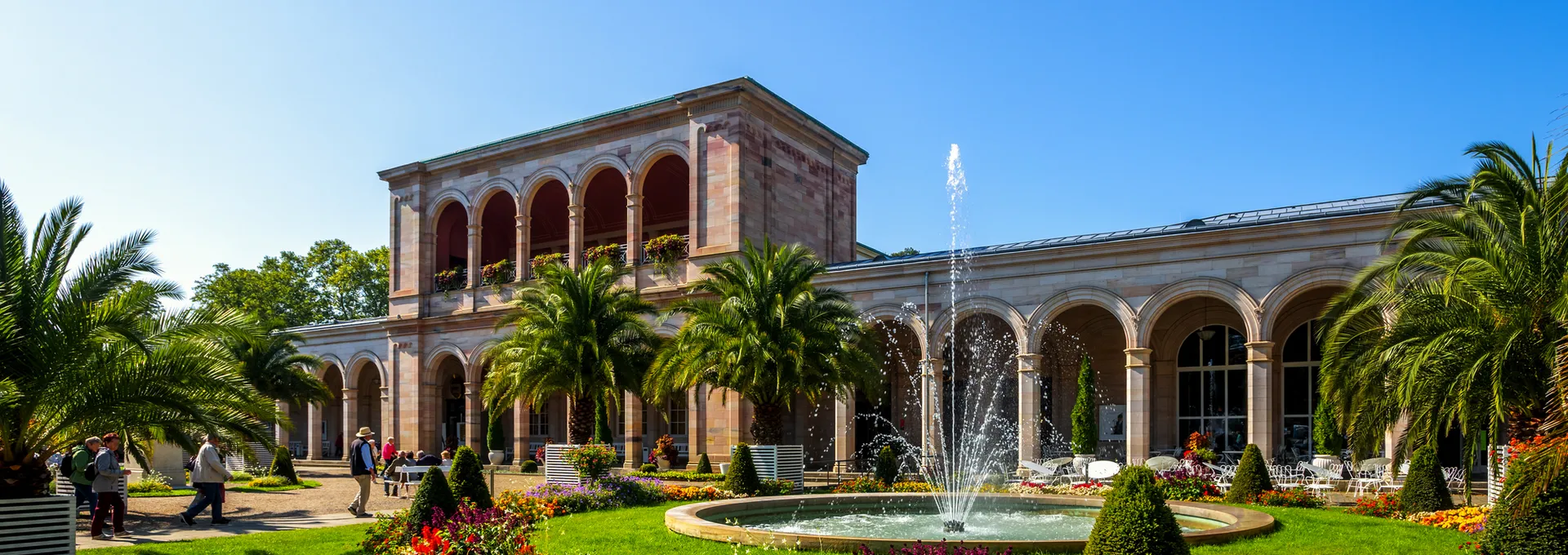 © Sina Ettmer - stock.adobe.com Historisches Gebäude mit Arkaden, Brunnen und Garten.