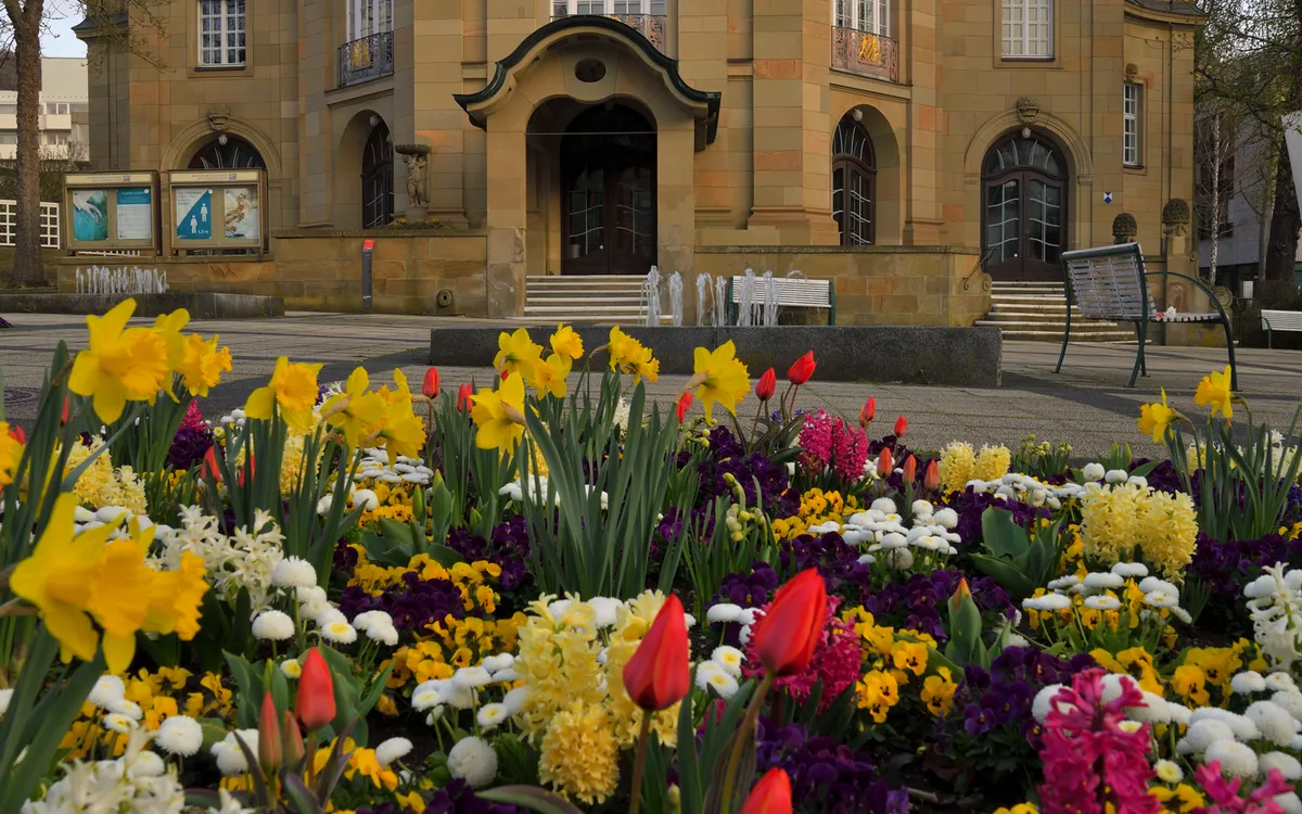 Kurtheater von Bad Kissingen im Frühling mit blühenden Blumenbeeten im Vordergrund.