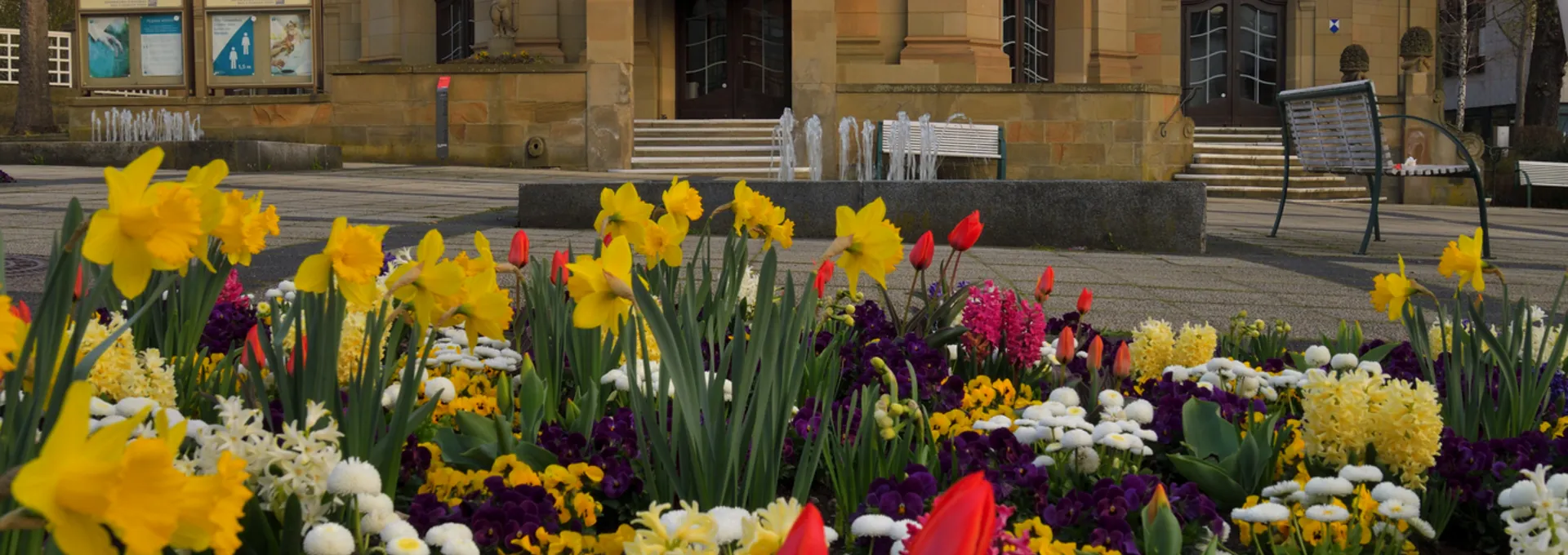 © OLIVER LAHREM SELIGENSTADT Kurtheater von Bad Kissingen im Frühling mit blühenden Blumenbeeten im Vordergrund.