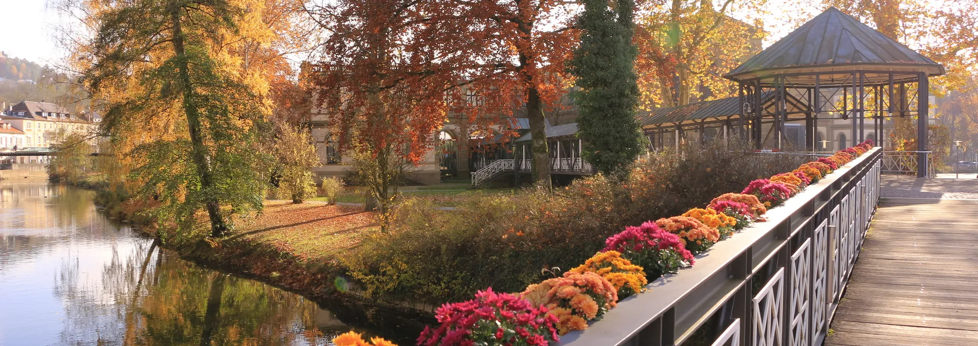 © Pixel62 - stock.adobe.com Brücke mit bunten Blumen, Herbstbäume im Hintergrund, See und Pavillon.