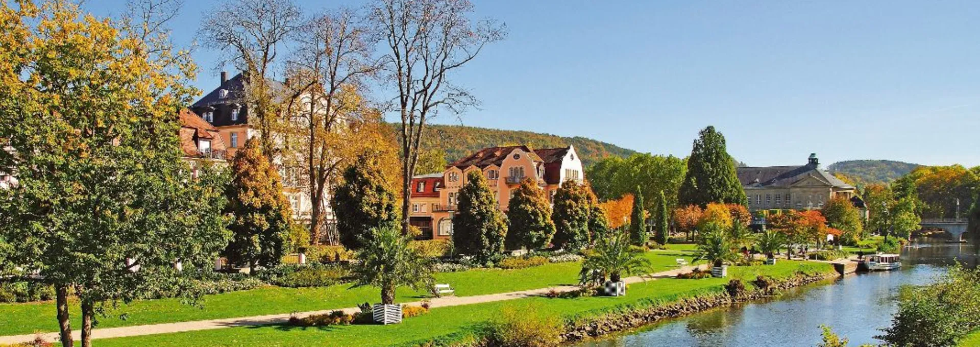 © travelpeter - Fotolia Fluss mit Parklandschaft, herbstlichem Laub und Häusern im Hintergrund.
