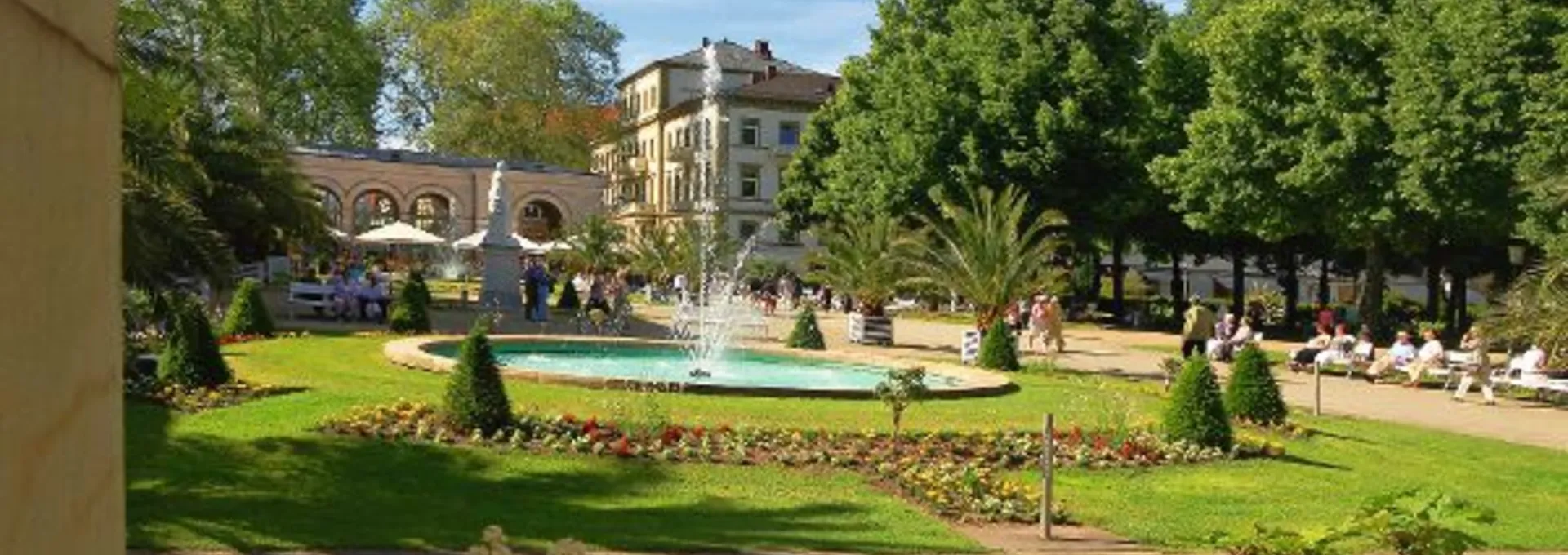 © Bayer. Staatsbad Bad Kissingen GmbH Springbrunnen im Kurgarten von Bad Kissingen, umgeben von Blumen und Bäumen.